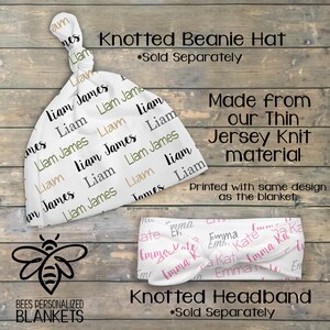 May include: A white knotted beanie hat with the name "Liam James" repeated in black, green, and brown text. The hat is made from a thin jersey knit material. A white knotted headband with the name "Emma" repeated in pink and gray text. Both items are sold separately.