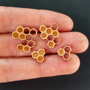 May include: Four wooden honeycomb shapes of varying sizes. The honeycomb shapes are cut from wood and have a natural wood color.