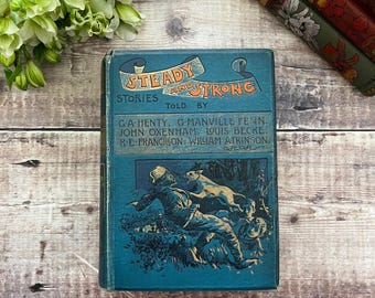 May include: A vintage book titled "Steady and Strong Stories" with a teal cover. The cover features illustrations of people and animals, with text in orange and white. The book is surrounded by other antique books and greenery.