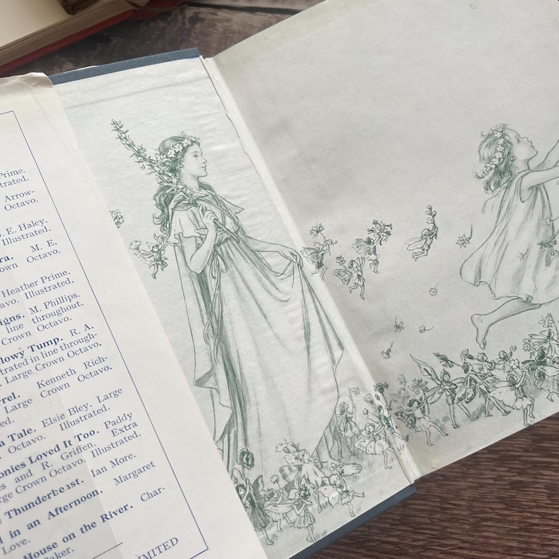 May include: An open book featuring delicate green illustrations of women and fairies. The drawings have a vintage feel, with detailed depictions of figures and floral elements. The aged pages suggest the book is antique.