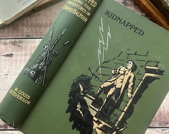 May include: A vintage copy of "Kidnapped" by R. Louis Stevenson. The book has a green cover with gold lettering and illustrations. The spine features crossed weapons. The cover illustration depicts a man on a rooftop with lightning.