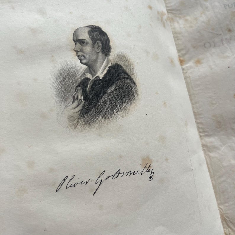 May include: A black and white engraving of a man holding a book. The engraving is on a page with the signature "Oliver Goldsmith" written in black ink.