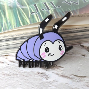 May include: A purple and black enamel pin of a cartoon pill bug with a smiling face and antennae.