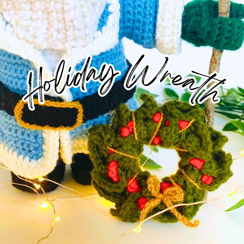 Peut inclure: Une couronne de No&euml;l en crochet de couleur verte avec des baies rouges et un n&oelig;ud dor&eacute;. La couronne est pos&eacute;e sur une surface blanche avec une figurine de P&egrave;re No&euml;l en crochet en arri&egrave;re-plan. Le texte "Holiday Wreath" est &eacute;crit en cursive noire au-dessus de la couronne.