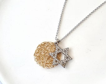 Pode incluir: Um colar de corrente de prata com um pingente de círculo dourado e um pingente de estrela de David de prata incrustado com pedras transparentes.