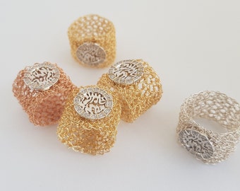 May include: Four crocheted rings with a silver, gold, and rose gold finish. Each ring features a circular design with Hebrew lettering and small clear stones.