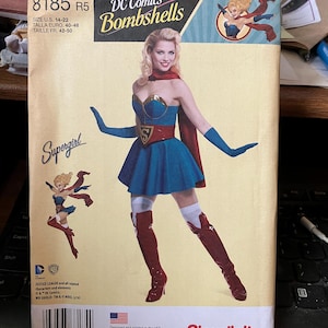 May include: A sewing pattern for a Supergirl costume from DC Comics Bombshells. The pattern is for sizes 14-22, 40-48 Euro, and 42-50 French. The pattern features a woman wearing a blue and red costume with a red cape and red boots. The pattern is designed and printed in the USA.