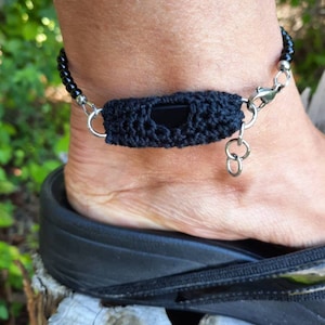May include: Black beaded ankle bracelet with a crocheted black band and a silver clasp.