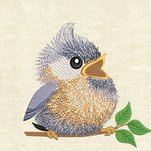 Puede incluir: Diseño bordado de un pájaro azul y amarillo con textura esponjosa, posado en una rama con hojas verdes. El pájaro tiene un pico grande abierto y un ojo negro.