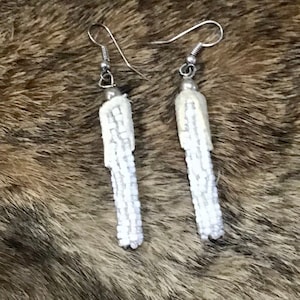 May include: A pair of white beaded tassel earrings with silver hooks.