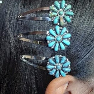 May include: Three silver-toned metal hair clips, each featuring a circular floral-shaped ornament. The ornaments are inlaid with multiple small, teardrop-shaped turquoise stones arranged in a radial pattern around a central stone.