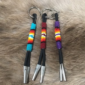 May include: Three beaded keychains with different colored beads and silver key rings. The keychains are made with black cord and have silver tips.
