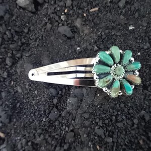 May include: A silver-toned metal hair clip featuring a decorative flower-shaped ornament. The ornament is composed of multiple teardrop-shaped turquoise stones arranged in a radial pattern around a small central stone, creating a floral design.