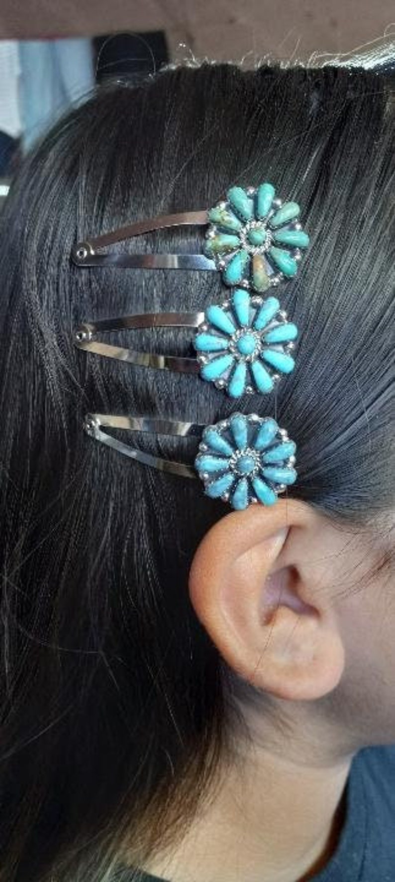 May include: Three silver-toned metal hair clips, each featuring a circular floral-shaped ornament. The ornaments are inlaid with multiple small, teardrop-shaped turquoise stones arranged in a radial pattern around a central stone.