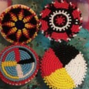 May include: Four round beaded ornaments with different designs. The first ornament is black, red, and yellow with a sun-like design in the center. The second ornament is red, white, and black with a circular design in the center. The third ornament is blue, white, red, yellow, and black with a circular design in the center. The fourth ornament is red, yellow, white, and black with a circular design in the center.