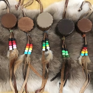 May include: Five leather pouches with colourful beaded tassels and feathers. The pouches are brown, black, and beige. The tassels are red, orange, yellow, green, and blue.