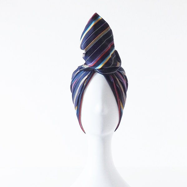 Shapeable cotton hair turban band with multicolor striped pattern on a dark blue background