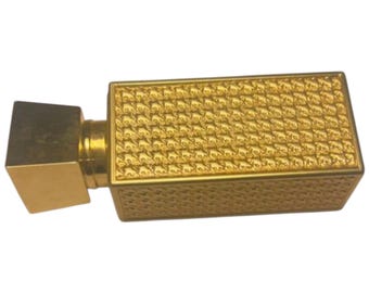 May include: A gold-colored perfume bottle with a square-shaped body and a textured design. The bottle has a square-shaped cap.