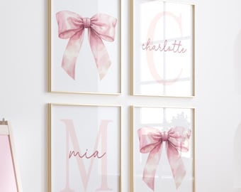 May include: Four gold framed prints with pink watercolor bows and the names Mia and Charlotte. Each print features a large pink letter.
