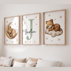 May include: Three framed prints with a woodland theme. The prints feature a brown bear sleeping on a crescent moon, a green letter J with the name Justin, and a brown bear sleeping on a cloud with gold stars.