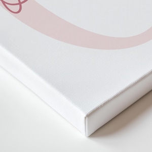 May include: A white canvas print with a light pink abstract design. The canvas is stretched over a wooden frame, with a clean, crisp edge. The artwork is displayed on a white surface, creating a minimalist aesthetic.