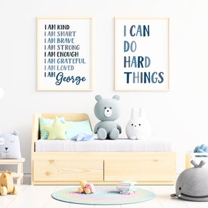 Pu&ograve; includere: Due stampe incorniciate con testo blu e bianco su sfondo bianco. La stampa a sinistra dice "Sono gentile, sono intelligente, sono coraggioso, sono forte, sono abbastanza, sono grato, sono amato, sono George". La stampa a destra dice "Posso fare cose difficili".