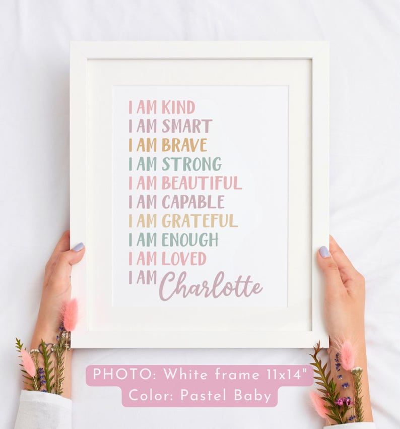 May include: A white framed print with pastel colored text that reads "I am kind, I am smart, I am brave, I am strong, I am beautiful, I am capable, I am grateful, I am enough, I am loved, I am Charlotte". The frame is 11x14 inches and the print is in pastel colors.