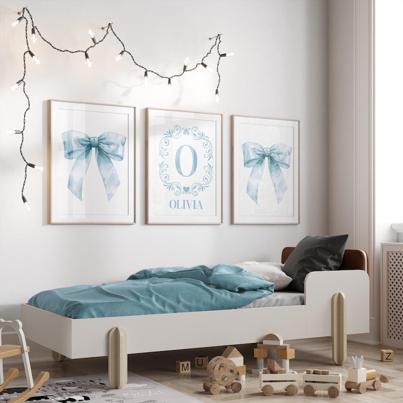 May include: Three framed prints with a blue watercolor bow design. The center print features the letter "O" in a decorative frame with the name "Olivia" below.