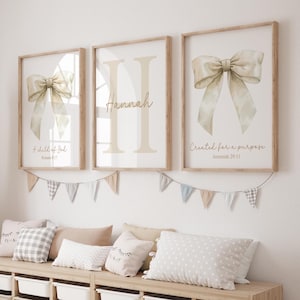 May include: Three framed prints featuring a watercolour bow design. The centre print displays the name "Hannah" in a script font. The left print includes the text "A child of God, Romans 8:17". The right print includes the text "Created for a purpose, Jeremiah 29:11".