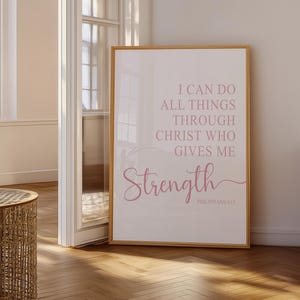 May include: A framed print with the words "I CAN DO ALL THINGS THROUGH CHRIST WHO GIVES ME Strength" in pink script. The print is in a room with a wooden floor and a wicker table.