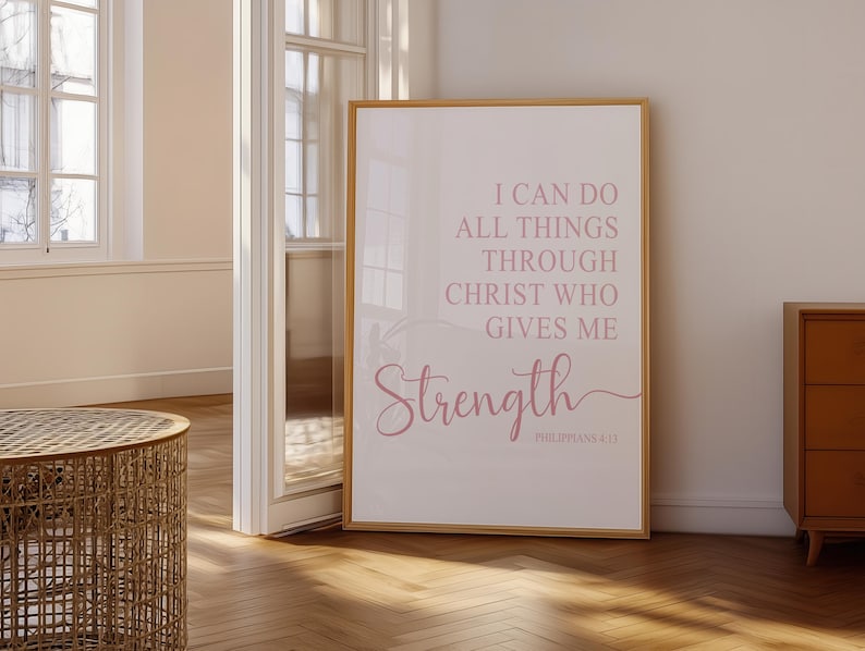 May include: A framed print with the words "I CAN DO ALL THINGS THROUGH CHRIST WHO GIVES ME Strength" in pink script. The print is in a room with a wooden floor and a wicker table.
