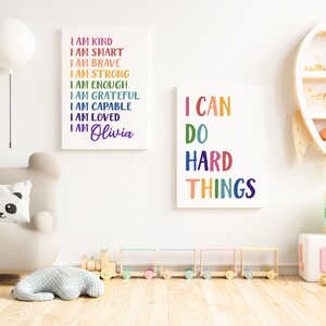 Pu&ograve; includere: Due stampe incorniciate con testo colorato su sfondo bianco. La prima stampa dice "Sono gentile, sono intelligente, sono coraggioso, sono forte, sono abbastanza, sono grato, sono capace, sono amato, sono Olivia". La seconda stampa dice "Posso fare cose difficili".