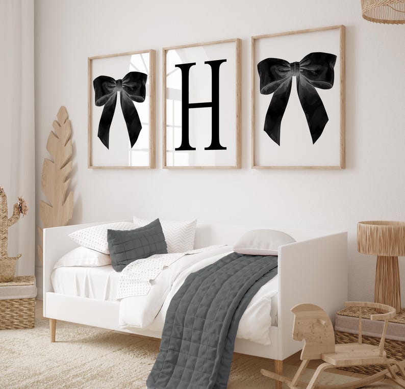 Peut inclure: Trois impressions encadr&eacute;es avec un n&oelig;ud noir et la lettre "H" sur fond blanc. Les impressions sont dans des cadres en bois clair. Un lit blanc avec une couette et des oreillers gris est au premier plan. Un cheval &agrave; bascule et une lampe en bois sont &eacute;galement visibles.