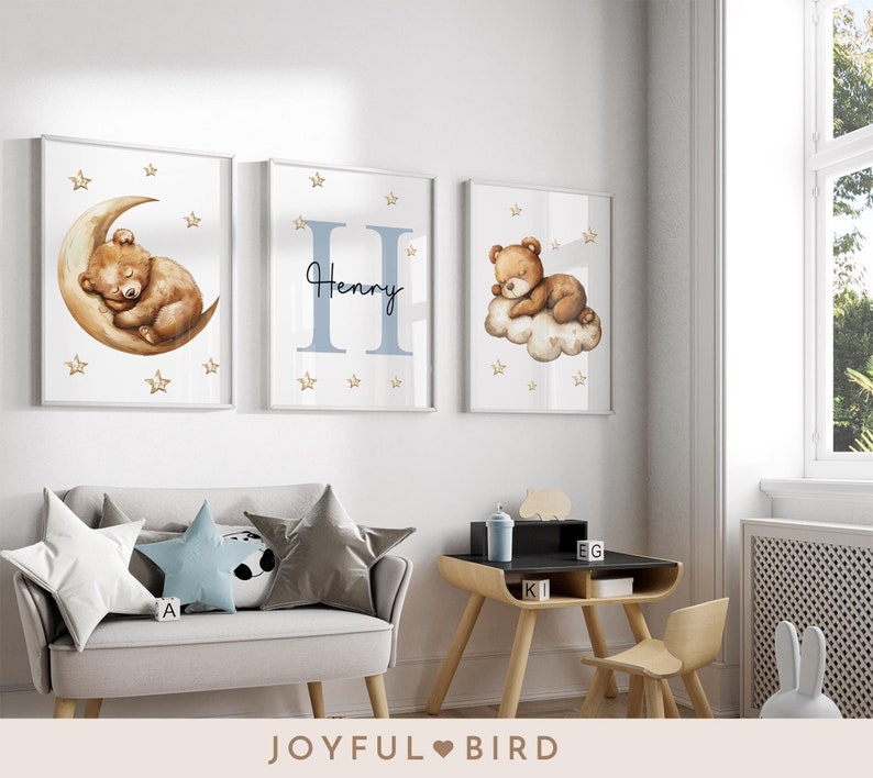 May include: Three framed prints with a nursery theme. The prints feature a sleeping bear on a crescent moon, a bear sleeping on a cloud, and the letter H with the name Henry. The prints are in a white frame with a white mat.