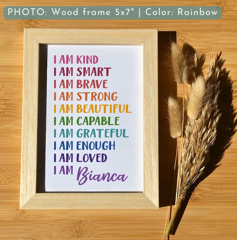 May include: A framed print with a rainbow-colored text that reads "I am kind, I am smart, I am brave, I am strong, I am beautiful, I am capable, I am grateful, I am enough, I am loved, I am Bianca". The frame is made of wood and is 5x7 inches.
