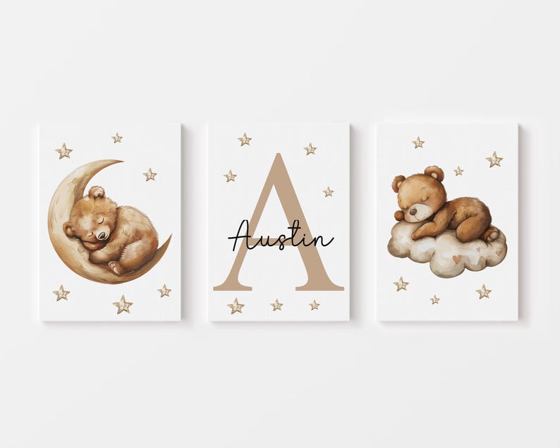 May include: Three nursery prints featuring a brown bear sleeping on a crescent moon, the letter A in brown, and a brown bear sleeping on a cloud. Each print has a white background with gold stars.