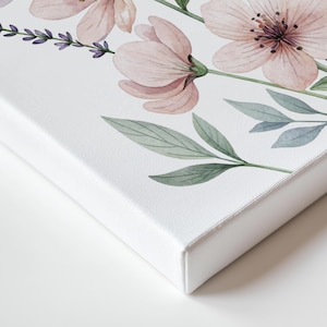 May include: A canvas art print featuring a watercolor floral design. The artwork showcases delicate pink flowers, lavender sprigs, and green leaves against a white background. The canvas has a clean, white edge, creating a modern aesthetic.