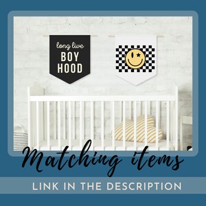 Peut inclure: Deux banni&egrave;res de cr&egrave;che noires et blanches accroch&eacute;es &agrave; un mur en briques blanches. Une banni&egrave;re dit "long live boyhood" et l'autre a un motif &agrave; carreaux noirs et blancs avec un smiley jaune avec une &eacute;toile.
