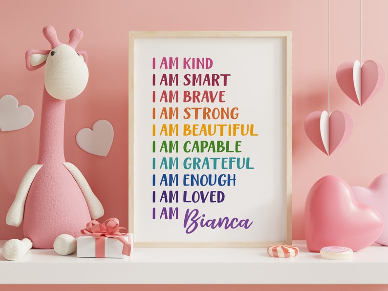 Op de afbeelding: Een ingelijst print met regenboogkleurige tekst die "Ik ben aardig, ik ben slim, ik ben dapper, ik ben sterk, ik ben mooi, ik ben bekwaam, ik ben dankbaar, ik ben genoeg, ik ben geliefd, ik ben Bianca" zegt.