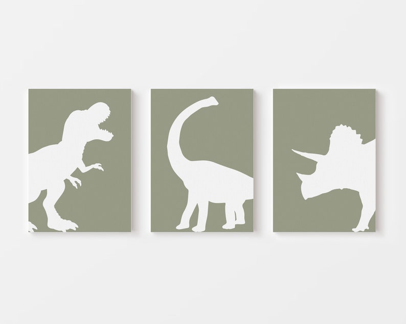 May include: Three dinosaur silhouettes in white on a sage green background. The dinosaurs are a Tyrannosaurus Rex, a Brachiosaurus, and a Triceratops.