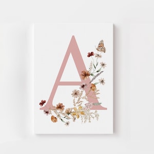 May include: A pink letter A with a floral wreath around it. The wreath includes small pink, white, and brown flowers, as well as green leaves and a butterfly.
