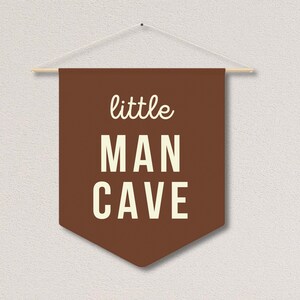 Peut inclure: Banni&egrave;re en feutre marron avec du texte blanc qui dit "little man cave".