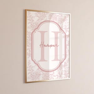 Peut inclure: Impression encadrée avec un motif floral rose et blanc. Le nom "Harper" est écrit en cursive, avec un grand "H" rose au centre. Le cadre est doré.