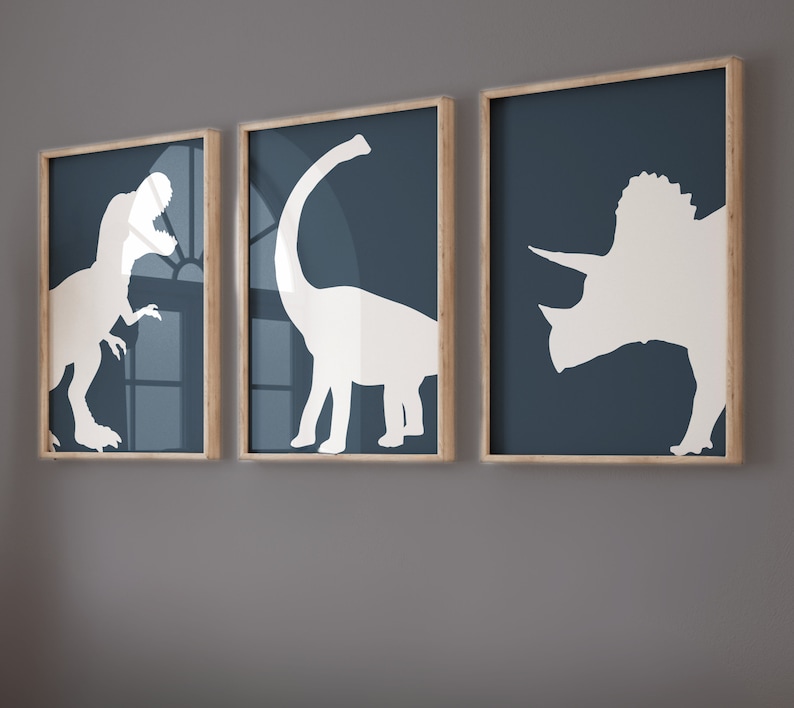 May include: Three framed prints with dinosaur silhouettes on a blue background. The dinosaurs are a Tyrannosaurus Rex, a Brachiosaurus, and a Triceratops.