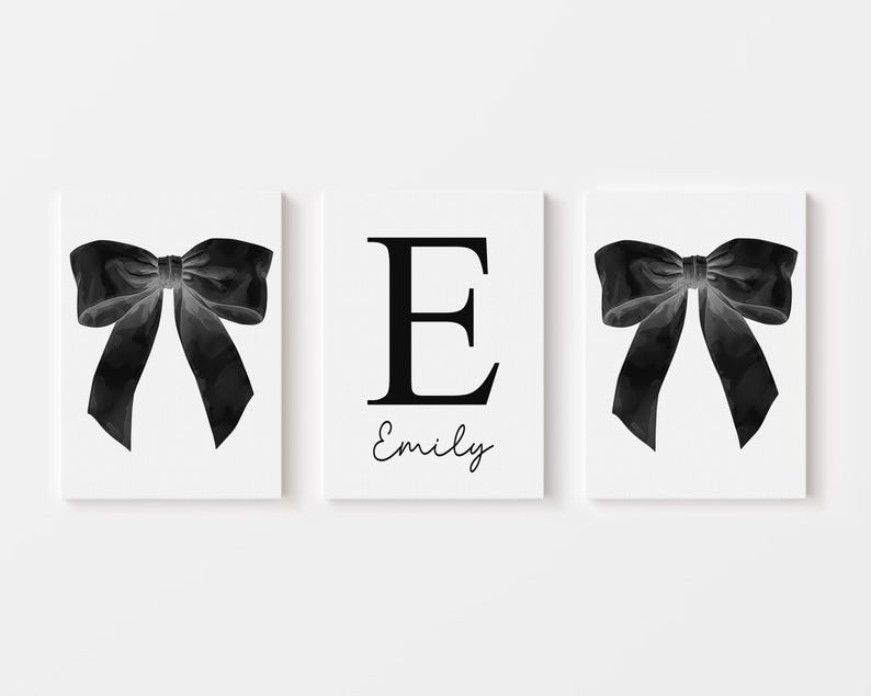 Peut inclure: Triptyque d'impressions d'art blanches. Deux impressions pr&eacute;sentent un n&oelig;ud noir &agrave; l'aquarelle. L'impression centrale affiche la lettre "E" en noir, avec le nom "Emily" en cursive en dessous. Le fond est blanc.