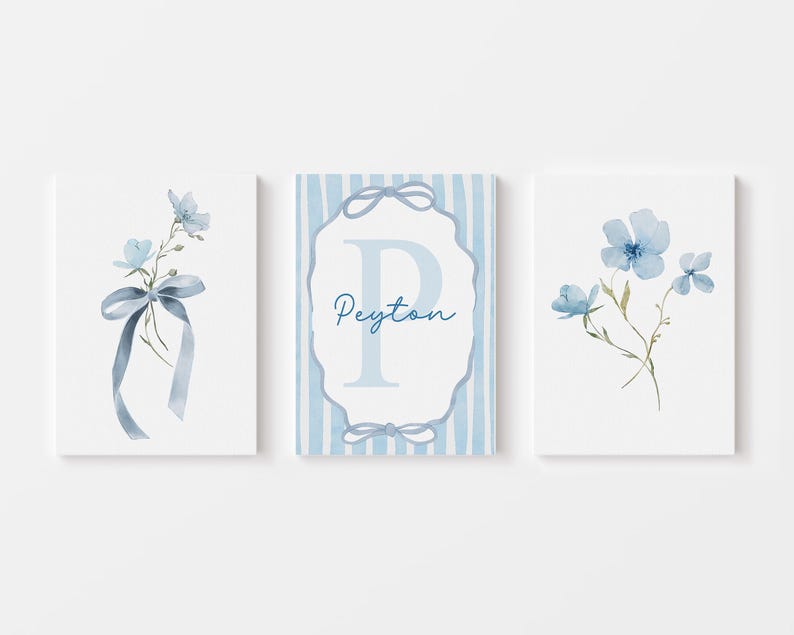May include: Three framed watercolor prints featuring blue floral designs. One print displays a bouquet with a ribbon, another has a floral arrangement, and the third showcases a monogram with the name "Peyton". The prints have a soft, pastel color palette.
