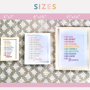 May include: Three framed prints with white backgrounds and rainbow text that reads "I am kind, I am smart, I am brave, I am strong, I am beautiful, I am capable, I am grateful, I am enough, I am loved." The prints are in different sizes: 5x7 inches, 8x10 inches, and 11x14 inches. The names "Alice", "Emily", and "Bianca" are at the bottom of each print.