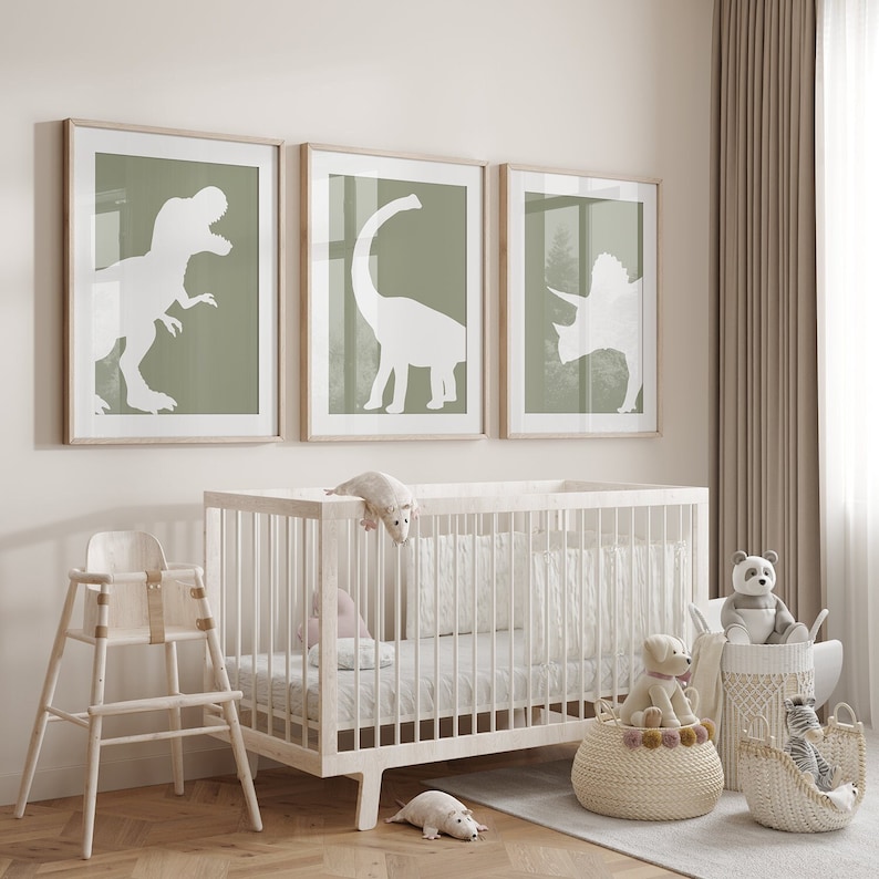 May include: A white crib with a white mattress and a white high chair in a nursery with three framed prints of dinosaur silhouettes on a light green background.