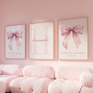 May include: Three pink framed prints with watercolour illustrations of pink bows. The left print says "A child of God" with a Bible verse. The middle print says "Hannah" and the right print says "Created for a purpose" with a Bible verse.