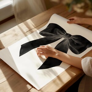 Peut inclure: Illustration d'un n&oelig;ud noir sur fond blanc. Le n&oelig;ud est grand et d&eacute;taill&eacute;, avec un aspect doux et translucide. L'&oelig;uvre est pr&eacute;sent&eacute;e sur une surface en bois.